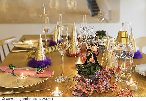 Festlich gedeckter Silvestertisch mit Tellern  Kerzen  Partyhüten  Sektflöten und Schornsteinfegerfiguren