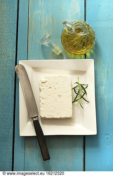 Feta cheese on plate beside oil bottle  close up