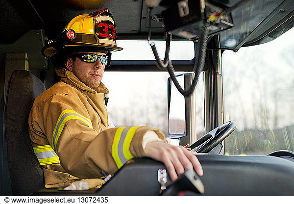 Feuerwehrmann mit Sonnenbrille im Feuerwehrauto sitzend
