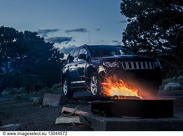 Fire pit by off-road vehicle against sky at dusk