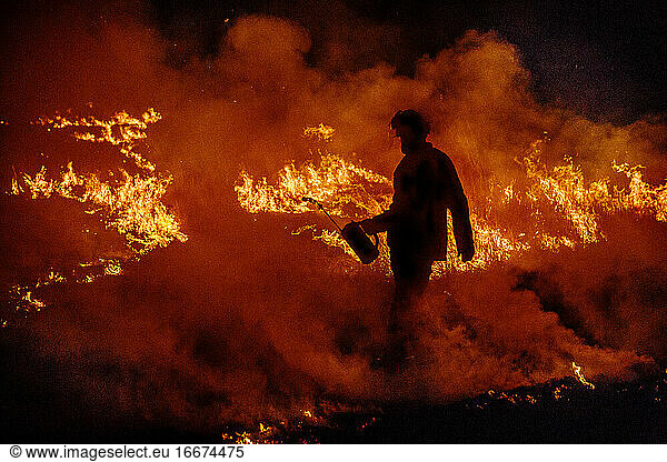 Firefighter with a drip torch walks through a wildfire in Australia