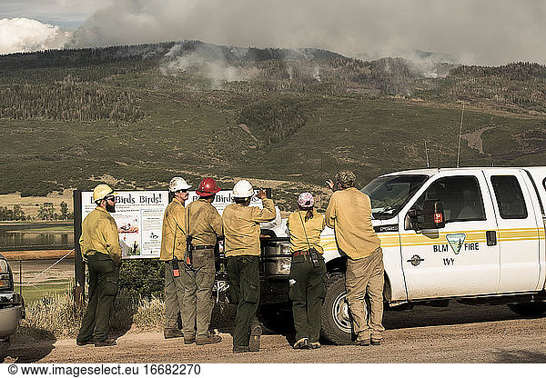 Firefighters discussing while smoke emitting from wildfire