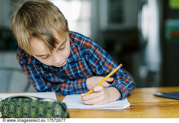 First grade boy doing his homework at the kitchen table