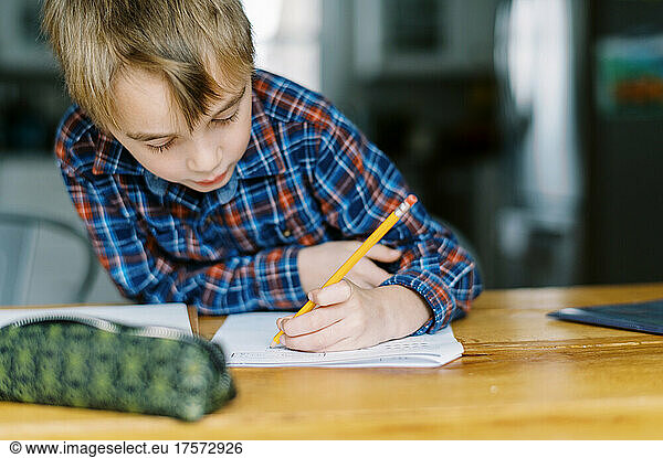 First grade boy doing his homework at the kitchen table