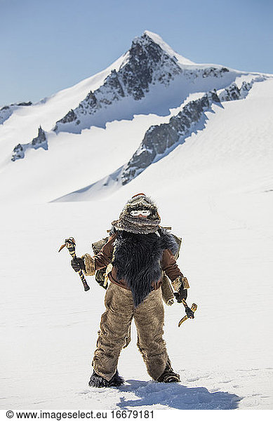 First Nations hunter wearing fur holding traditional ice ax tools.