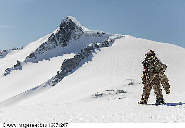 First nations original explorers crossing glacier toward mountain.