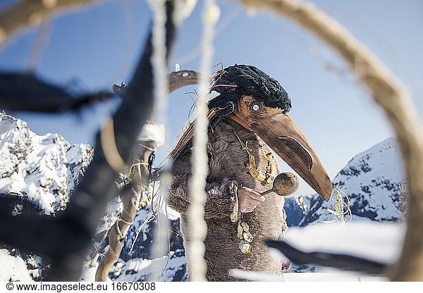 First Nations person dressed in Ravens mask preforms a ceremony.