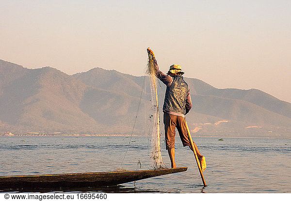 Fischer  der bei Sonnenuntergang balanciert und fischt