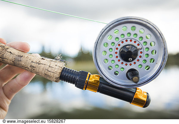 Fischer hält Fliegenfischerrute.