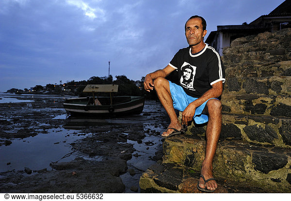 Fischer mit ernstem Gesichtsausdruck und Che Guevara T-Shirt im Fischerhafen von Guaratiba