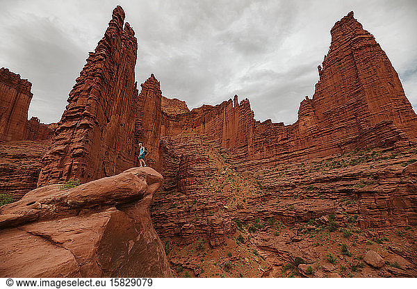 fischertürme aus rotem sandstein erheben sich über einem männlichen wanderer in der nähe von moab utah