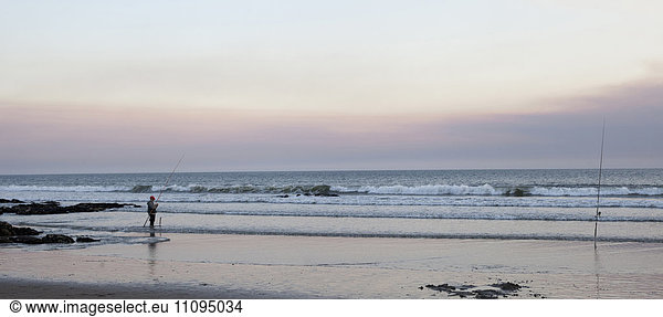 Fisherman fishing on beach during dusk  Viana do Castelo  Norte Region  Portugal