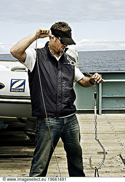 fisherman holding shark hook on deck