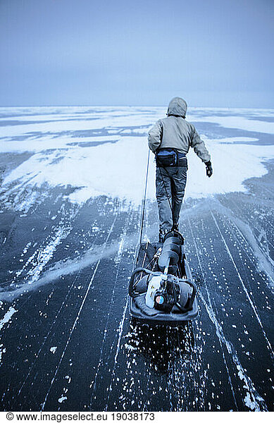 Fisherman pulls a sledge over a frozen lake in Canada