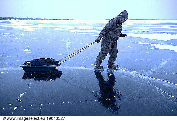 Fisherman pulls sled over thick ice on Lake Simcoe
