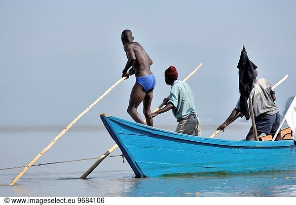 Fishers pushing their boat through the water at Lake Victoria  Kenya.