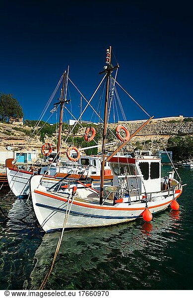 Fishing boats moored in crystal clear turquoise sea water in harbour in Greek fishing village of Mandrakia  Milos island  Greece. Horizontal camera pan