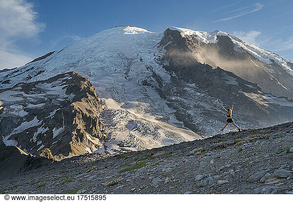 Fit female jumping with excitement on a ridge next to Mount Rainier