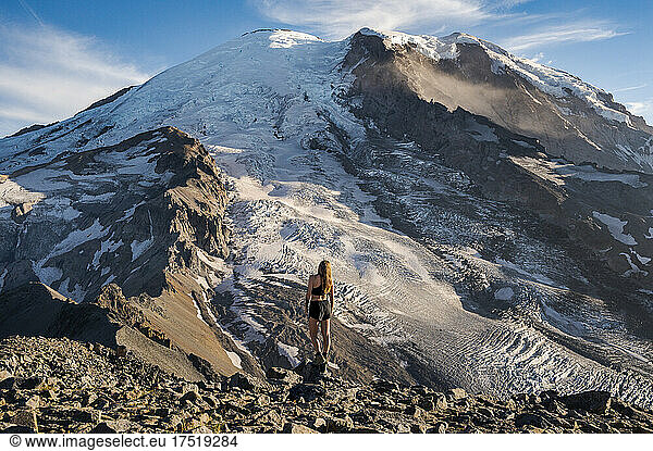 Fit female standing on a cliff next to Mount Rainier