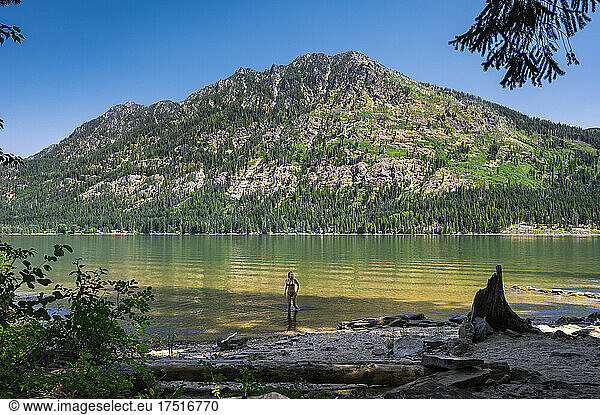 Fit girl in bikini standing in a beautiful mountain lake