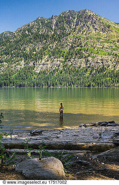 Fit girl in bikini standing in mountain lake in a summer day