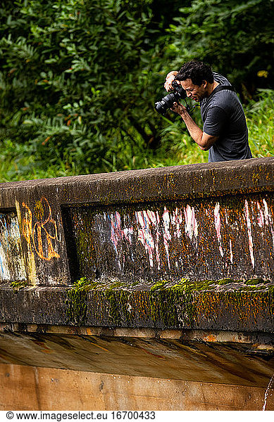 Fit male takes a photo off an old bridge