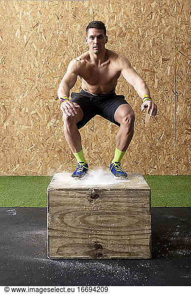 Fit man jumping on a gym box for workout