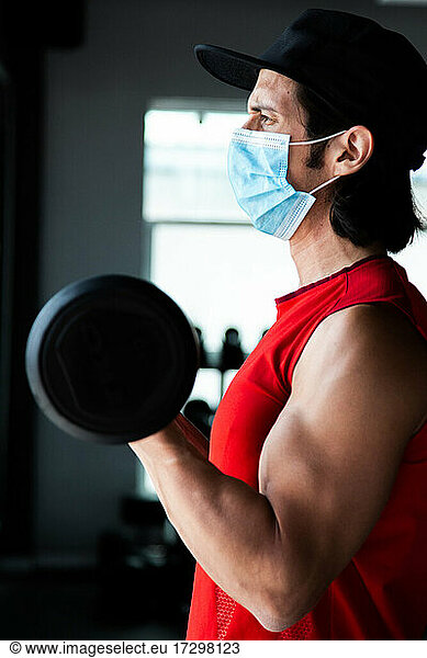 Fit mexican guy training curl biceps at gym during COVID pandemic