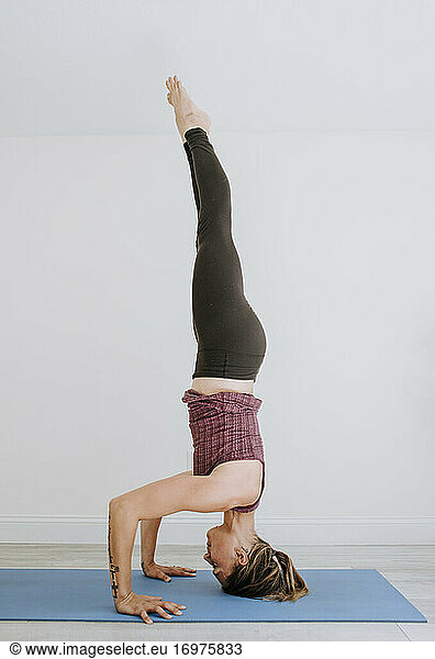 Fit muscular athletic woman does headstand while practicing yoga