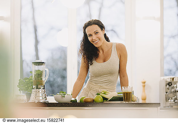 Fit woman standing in kitchen  preparing healthy smoothie