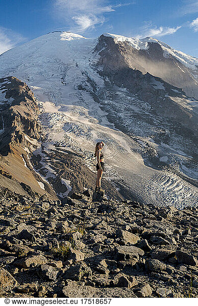 Fit young female standing on a cliff next to Mount Rainier