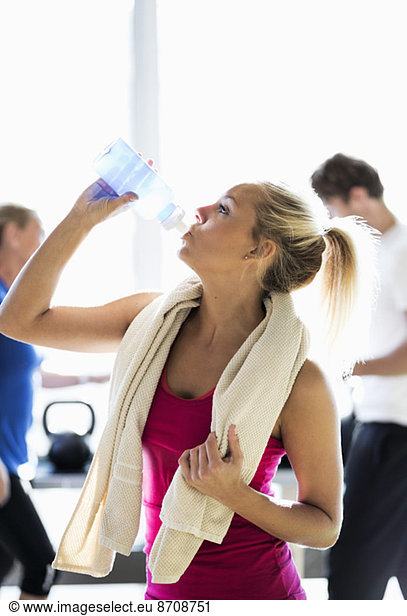 Fit young woman drinking water at health club