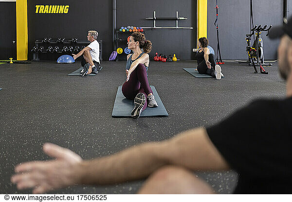 Fitness coach instructing athletes exercising in gym
