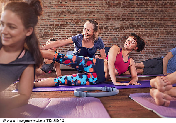 Fitness instructor adjusting young woman in exercise class gym studio