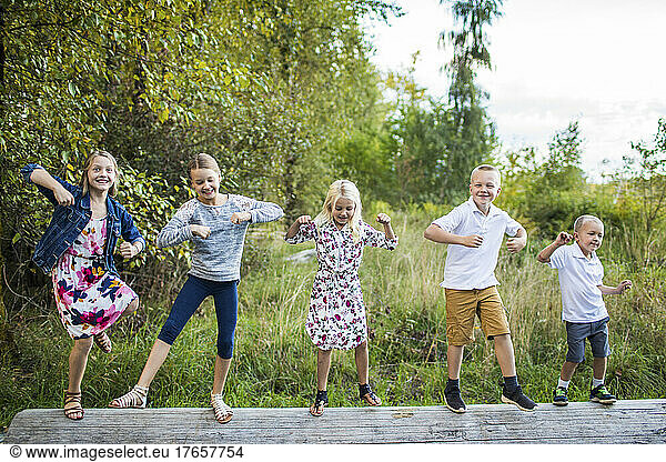 Five cute kids dancing outdoors on log