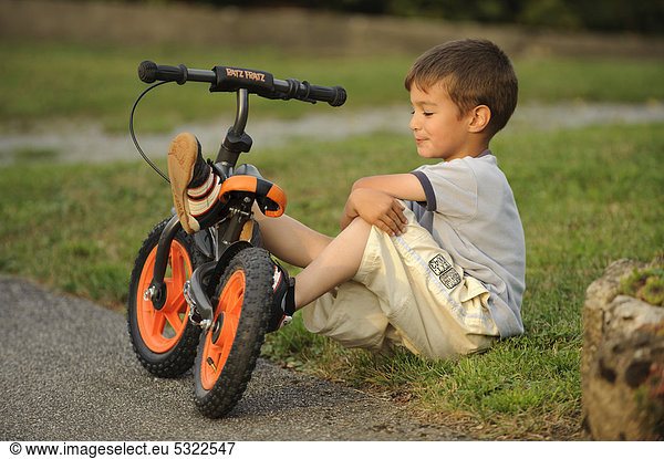 Five-year-old boy with training bike resting