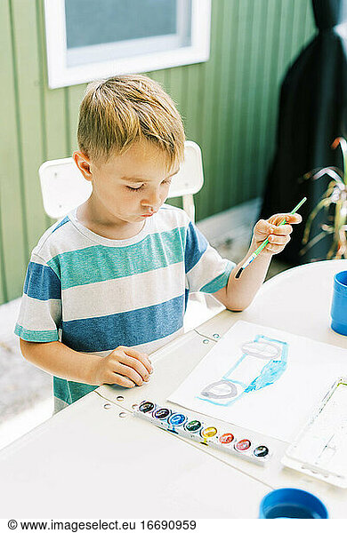 Five year old painting with watercolors outside on the patio