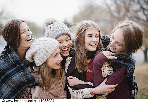 Five young people  girls  friends in warm shawls and woolly hats outdoors.