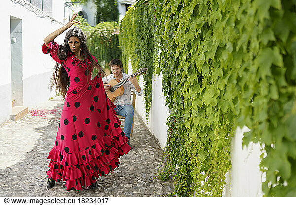 Flamenco dancer and guitarist performing by wall with ivy plants