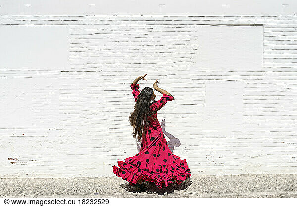 Flamenco dancer spinning in front of white wall