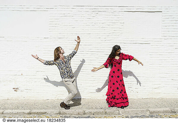 Flamenco dancers performing in front of white wall on sunny day