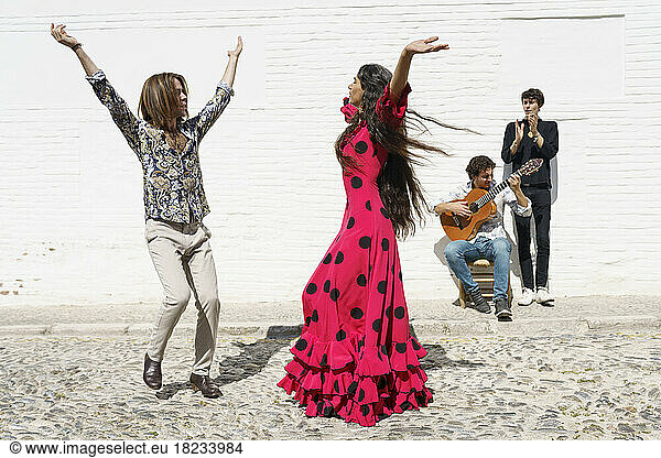 Flamenco dancers performing with guitarist on sunny day