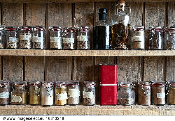 Flaschen mit Gewürzen und Gewürzmischungen in Holzregal. Verschiedene Bio-Kräuter für die Küche im Vintage-Look Viele.