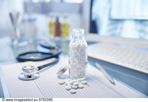 Flask with white pills  chart and stethoscope on desk