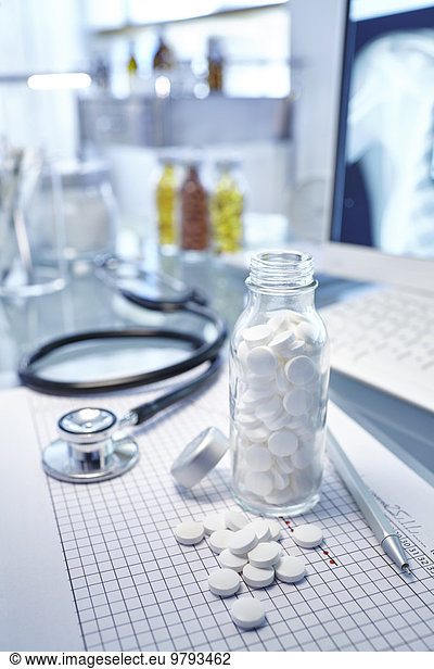 Flask with white pills  chart and stethoscope on desk
