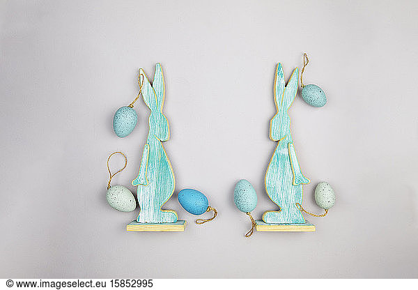 Flat lay of two wooden easter bunnies and six easter eggs.