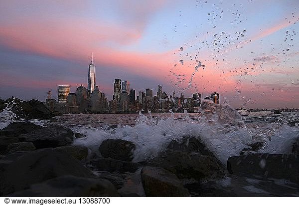 Fließender Fluss gegen das Stadtbild in New York City in der Abenddämmerung