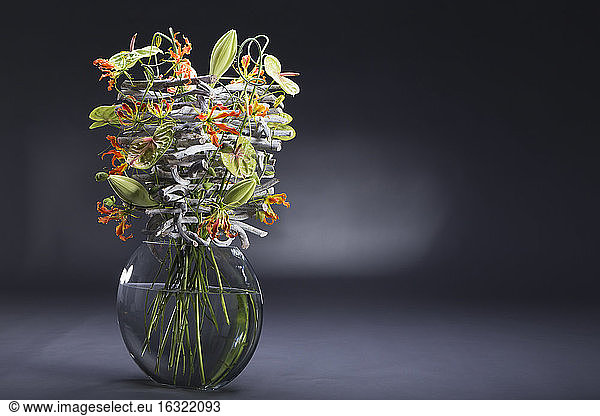 Floral arrangement of stone wood  Allium sativum  Anthurium  Gloriosa superba  Lilium longiflorum  Passiflora caerulea