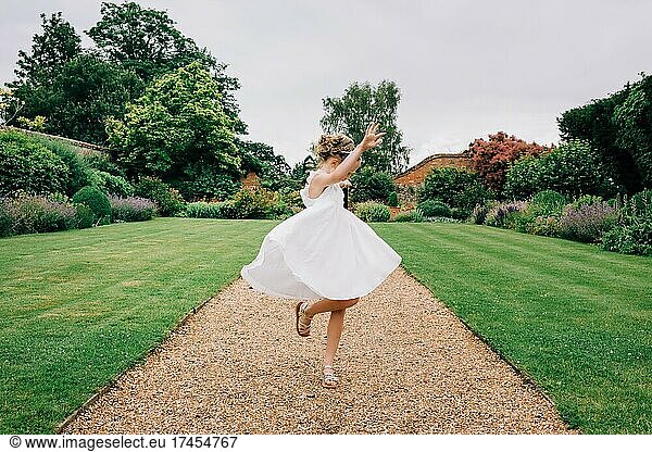flower girl dancing in a beautiful dress around a country garden