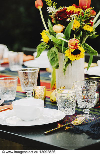 Flower vase with crockery arranged on table in backyard